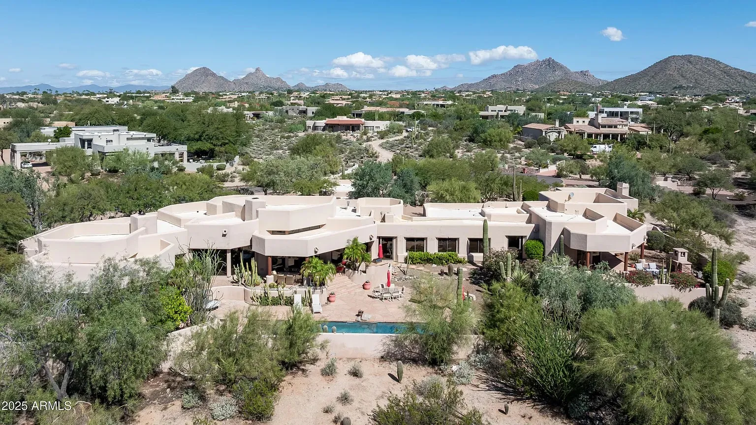 Aerial view of a sprawling Scottsdale estate with pool, saguaros, and the McDowell Mountains beyond